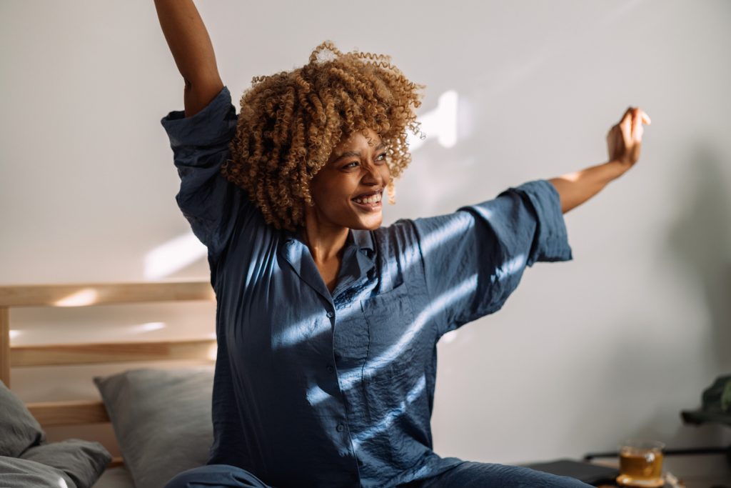 Smiling patient free from neck pain waking up and stretching in the morning
