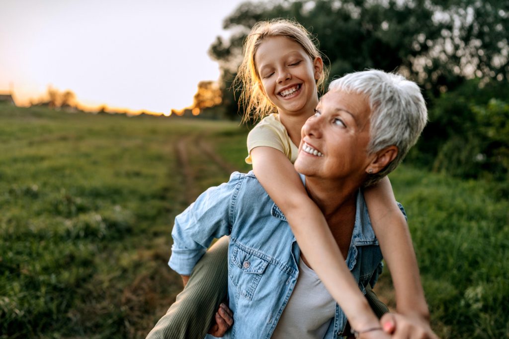 Woman carries granddaughter on back after recovery from spinal reconstruction surgery