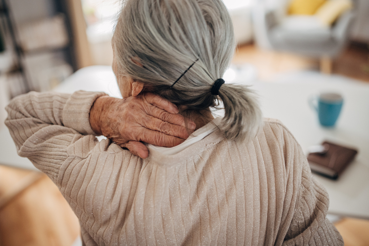 Woman with hand on back of neck indicating pain