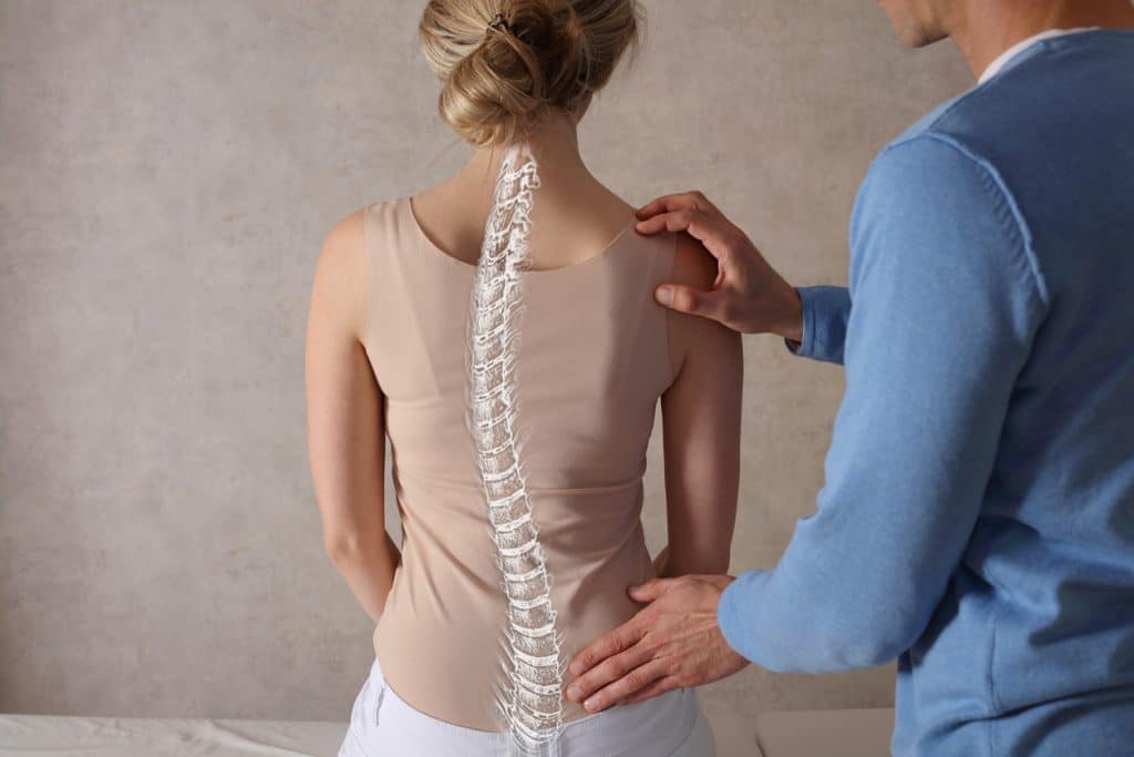 Physician evaluates scoliosis in patient