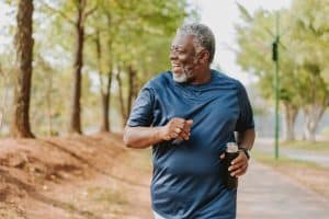 Cheerful senior in activewear running at public park
