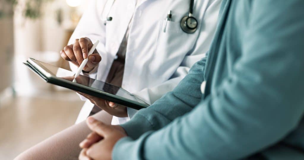 Neck pain specialist using tablet to explain treatment to patient