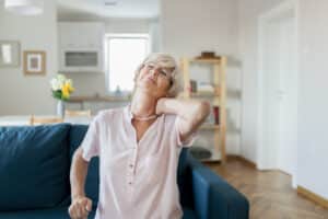 Senior person at home holding neck in pain