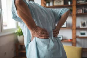 Senior person holding back in pain at home