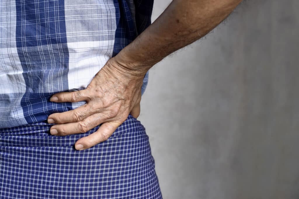 Close image of man holding right side of his back