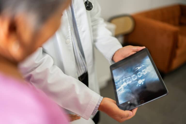 Doctor showing spine X-ray on tablet to patient