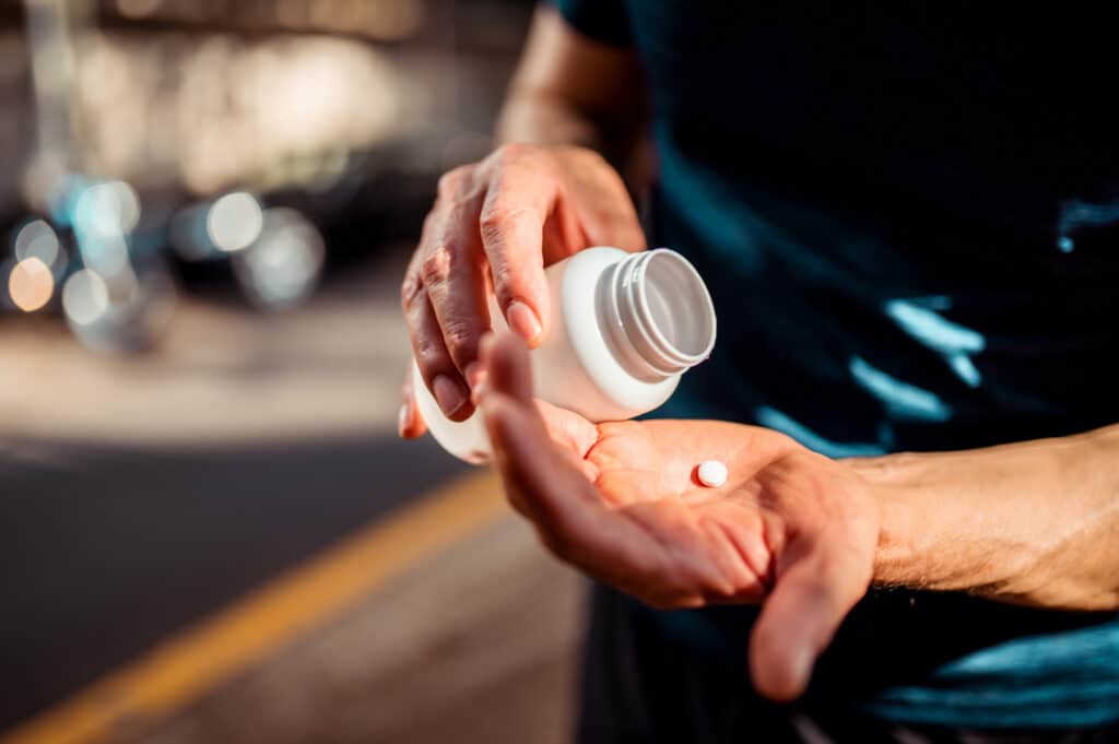 Close image of person removing pill from bottle