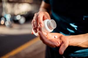 Close image of person removing pill from bottle