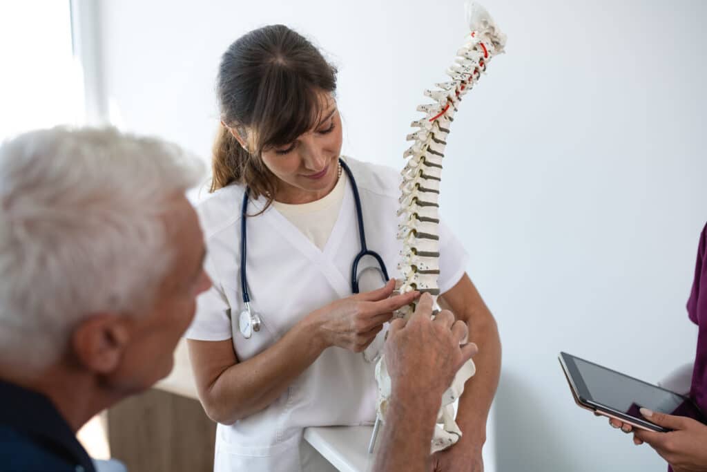Doctor pointing at lumbar spine model and talking to patient