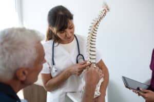 Doctor pointing at lumbar spine model and talking to patient