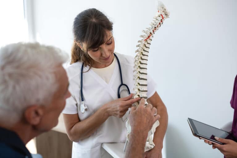 Doctor pointing at lumbar spine model and talking to patient