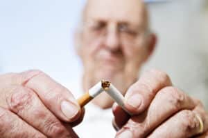 Older individual breaking cigarette in half