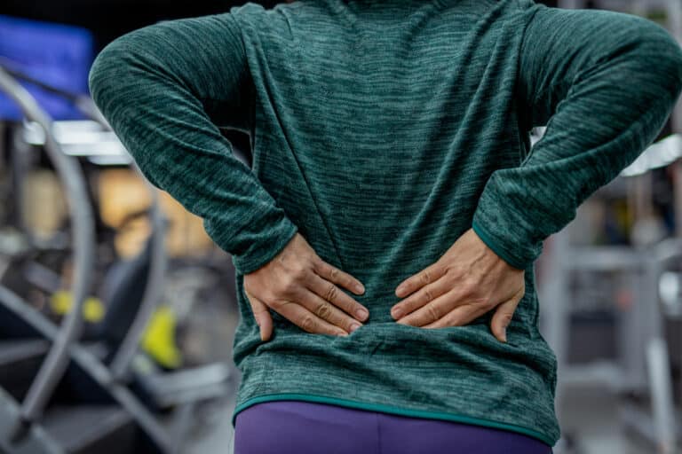 Person holding lower back at gym